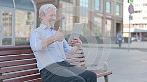 Old Man Celebrating Online Win on Tablet while Sitting Outdoor on Bench