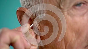 Old man is cleaning ear with a cotton swab. morning routine, personal hygiene concept