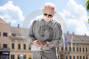 Old man cleaning hands with wet wipes outdoor