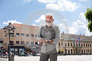 Old man cleaning hands with wet wipes outdoor