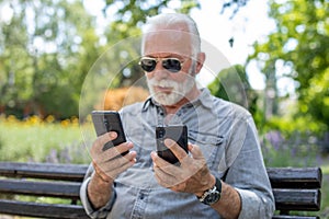 Old man compare two smartphones photo