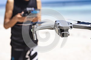 An old man controlling a small drone at the beach. A Hobbyist drone operator flying outdoors