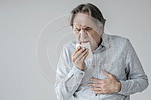 Old man coughing to tissue