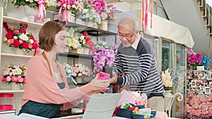 Old man customer payment by scanning phone application to female florist owner.