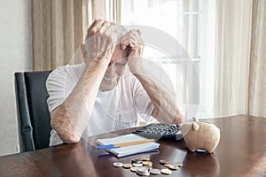 old man in a depression counts pennies from the pension fund. worried elderly man puts money in a piggy bank. impact of