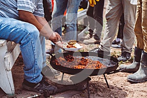 Old man distributing the traditional food on the open fire