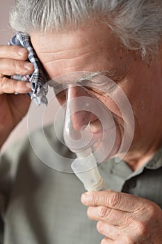 An old man doing inhalation