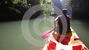 old man drifts on kayak down river along sunlit canyon