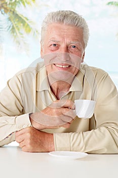 Old man drinking coffee at table
