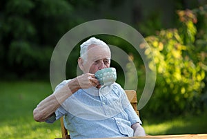 Old man drinking tea in garden