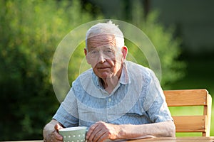 Old man drinking tea in garden