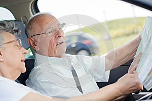 Old man driving car while checking map