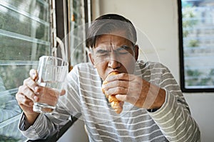 Old man eating Enjoy croissant