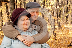 Old man embrace old woman in autumnal forest