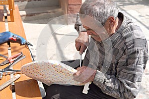 Old man fixing broken chair with screwdriver