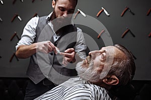 Old man getting his beard shaved by barber