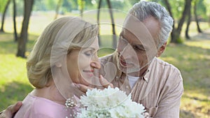 Old man giving bunch of flowers to wife, celebrating marriage anniversary