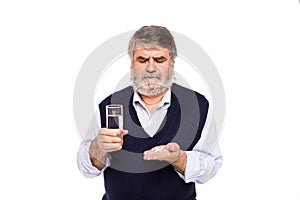 Old man with glass of water and pills in hands