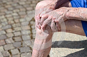 Old man with gnarled hands clutching his knee