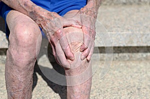 Old man with gnarled hands clutching his knee