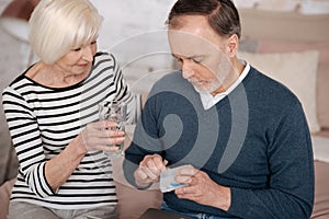 Old man going to take pills near his wife