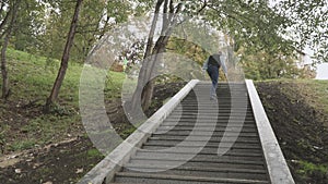 Old man is going up the stairs in park