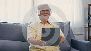 Old man grandfather smile relaxing wear headphones is listening to music using a digital tablet