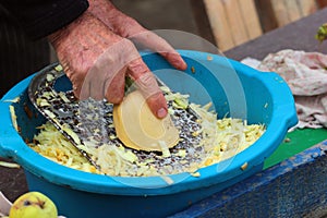 Old man grates a squash. Hands hold grater and vegetable photo