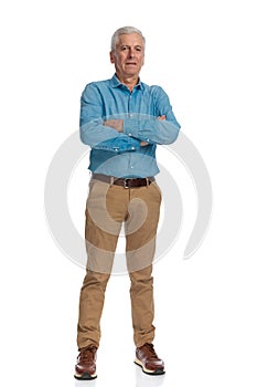 Old man with grizzle hair crossing arms and posing while standing