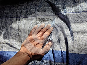 Old man hand on blue cloth with beautiful pattern