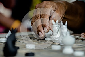 Old man hand moving Thai Chess Figure on Wood Checkerboard photo