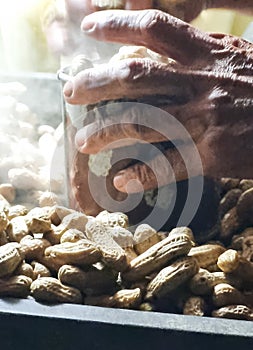 Old man hand serve boiled peanuts on stall street market