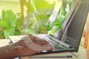 old man hand using laptop on desk background blurred nature