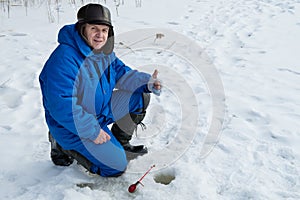 Old man hands up during fishing on lake at cold winter day