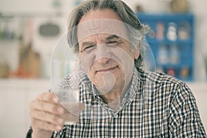 Old man having glass of water in kitchen