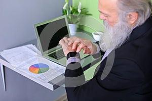 Old man head leader completes working day, sitting at laptop at