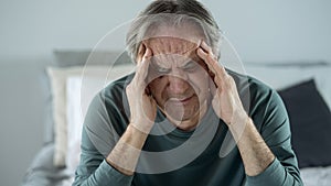 Old man holding his head with his hands