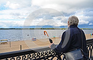 Old man holding vintage umbrella looking far