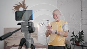 Old man Influencers blogging on healthy lifestyle content recording exercises on phone camera during a live broadcast