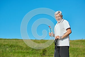 Old man keeping water bottle and tracking sticks.