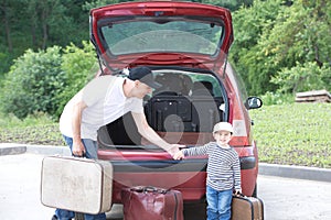 Old man and kid loads his red car suitcases