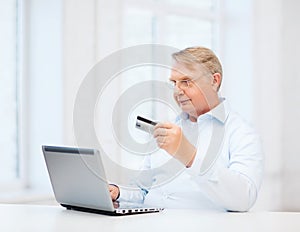 Old man with laptop and credit card at home