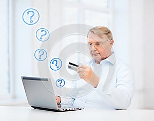 Old man with laptop and credit card at home