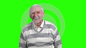 Old man laughing in green studio, slow-motion.