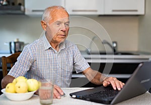 Old man learning to use laptop at home