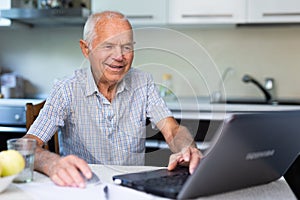 Old man learning to use laptop at home