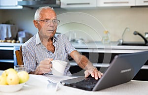 Old man learning to use laptop at home