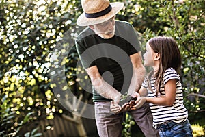 Old man with little girl gardening on their backyard