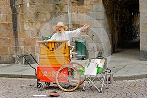 An old man with long white bread plays his street organ.