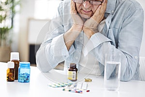 Old man looking at pills desperately